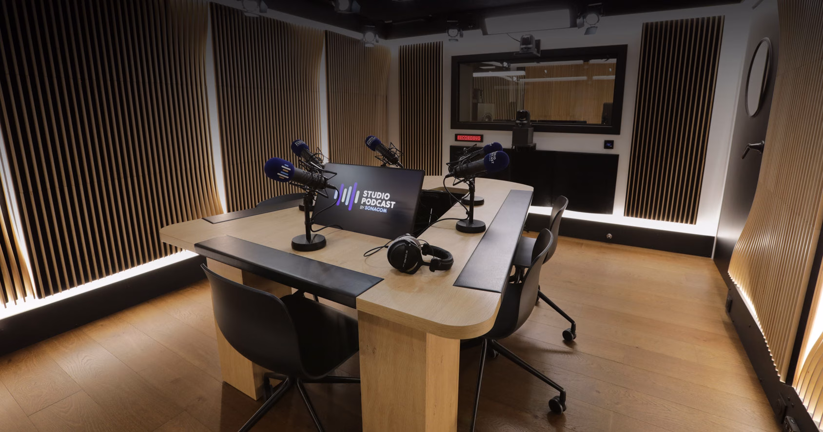 The studio desk with its microphones and headphones, the control room behind the glass