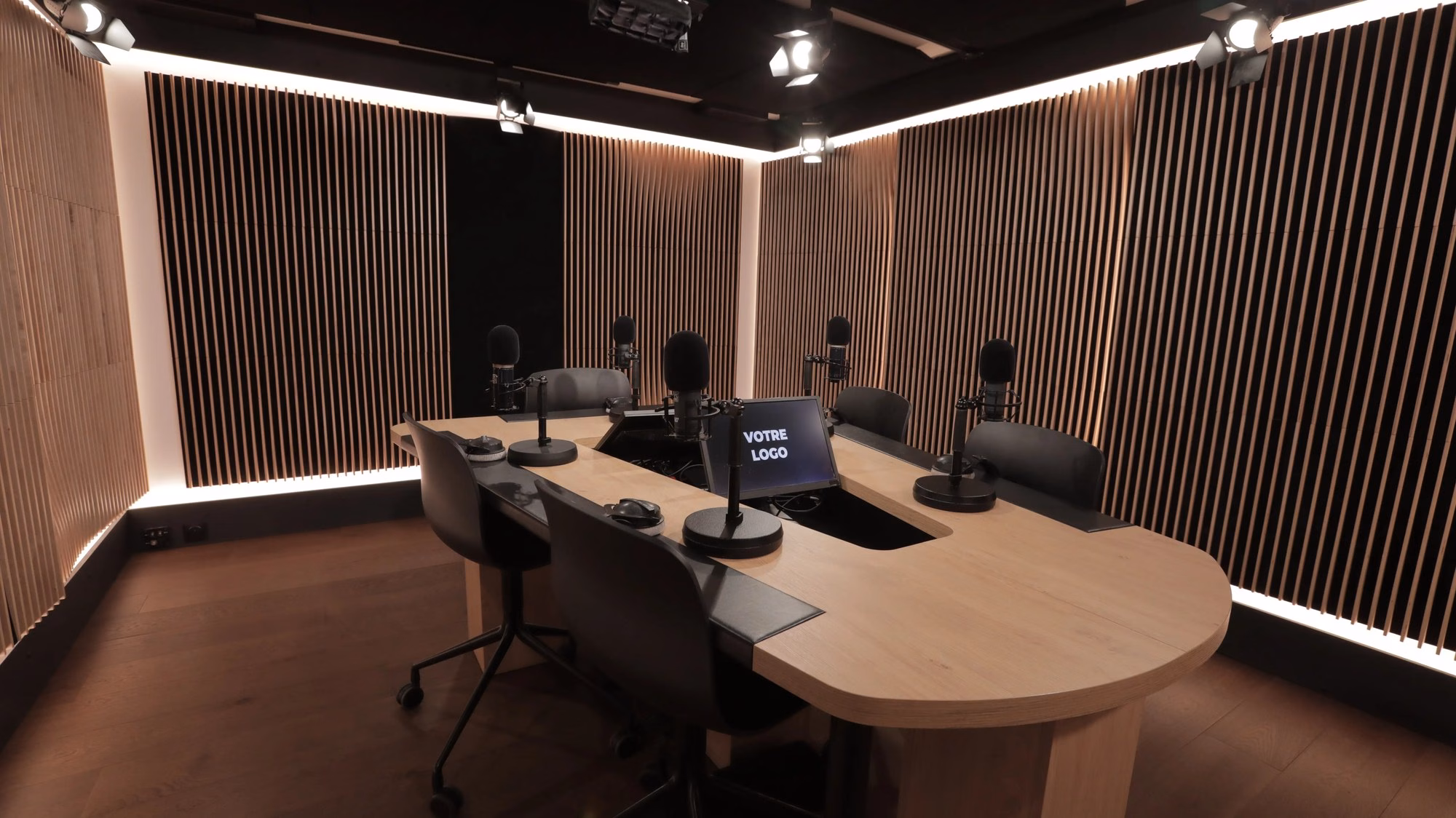 Le studio podcast en entier : le desk en bois, les micros, les caméras et les panneaux acoustiques