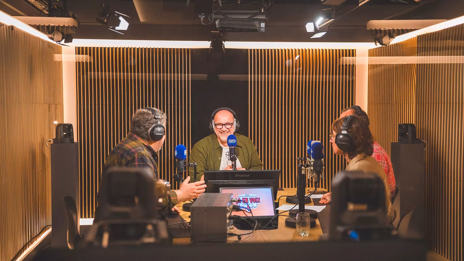 A recording session at the podcast studio: three people at the mic around the desk